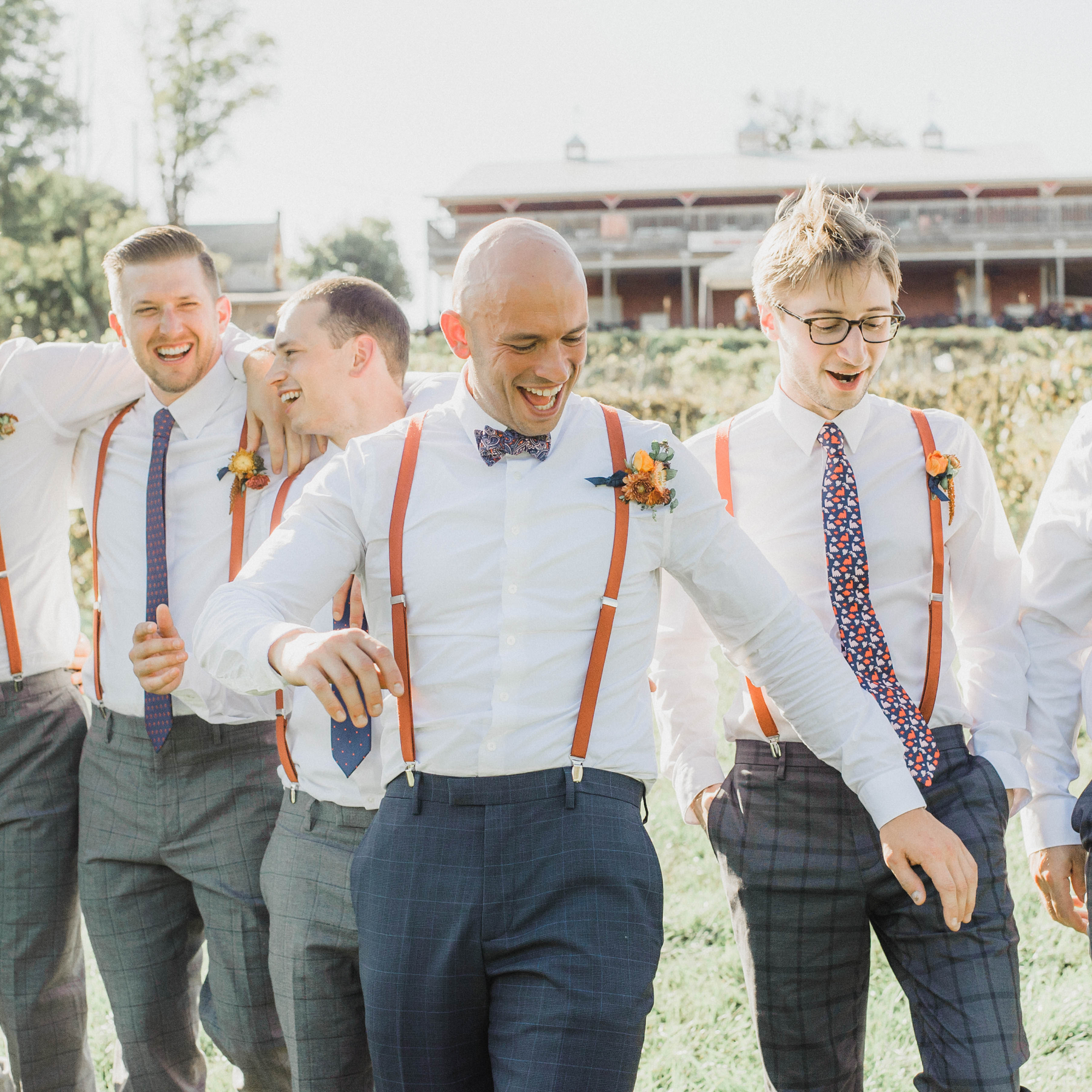 happy groomsmen and groom in suspenders and mixed patterned neckties