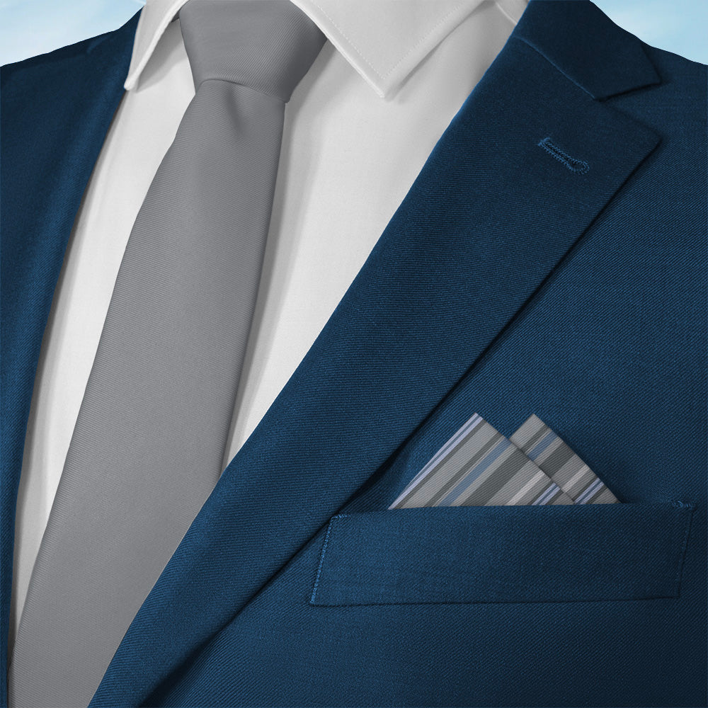 Blue suit jacket with a gray tie and striped pocket square on a light blue background