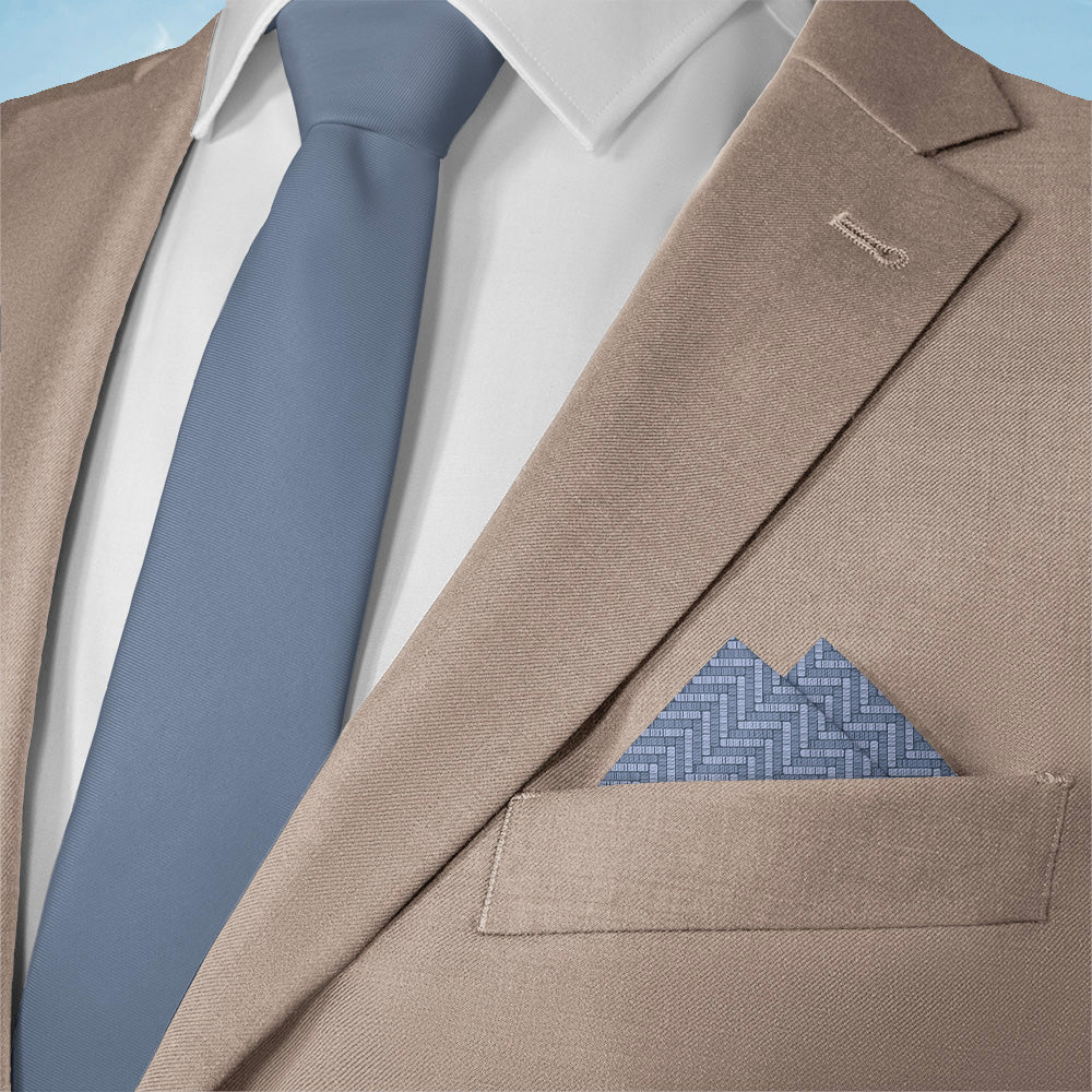 Beige suit jacket with a blue tie and textured pattern pocket square.