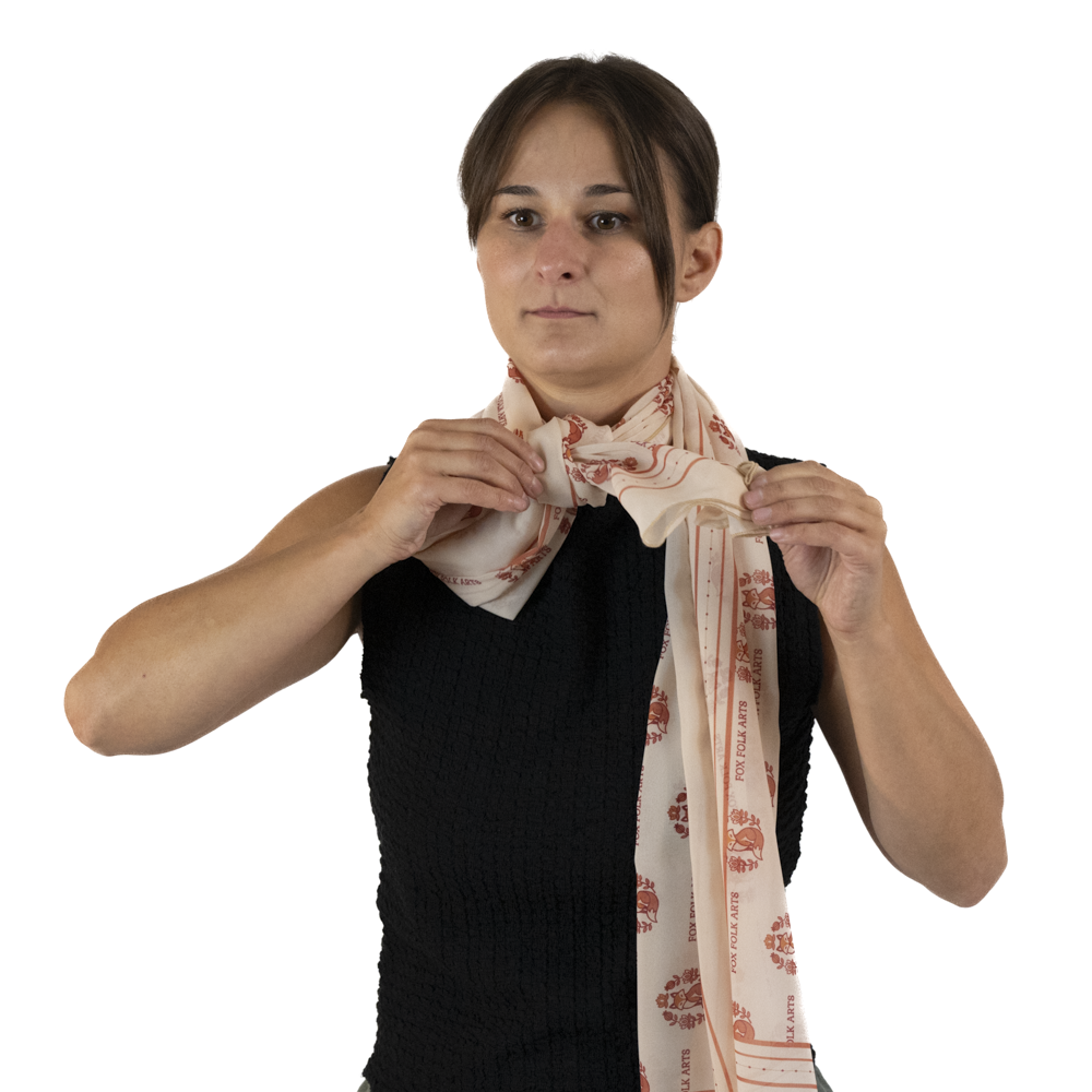 A woman threading the end of the rectangle scarf around her neck through the knot in the scarf.
