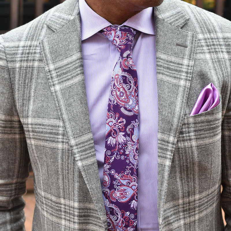 Gray checkered blazer with a purple shirt, patterned tie, and pocket square.