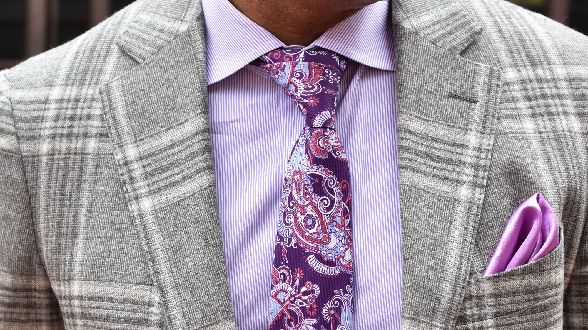 Gray checkered suit with a purple shirt, pink paisley tie, and matching pocket square.