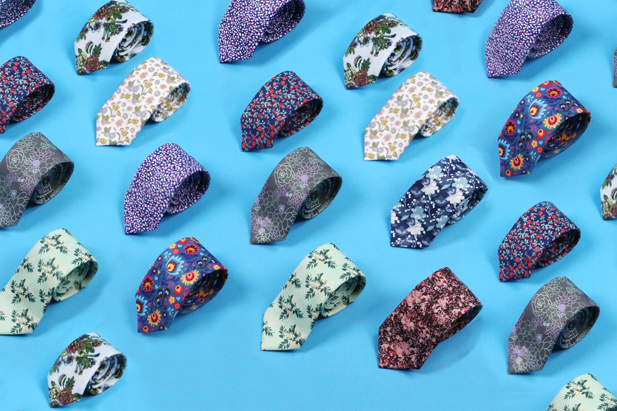 Rolled floral patterned neckties on blue background