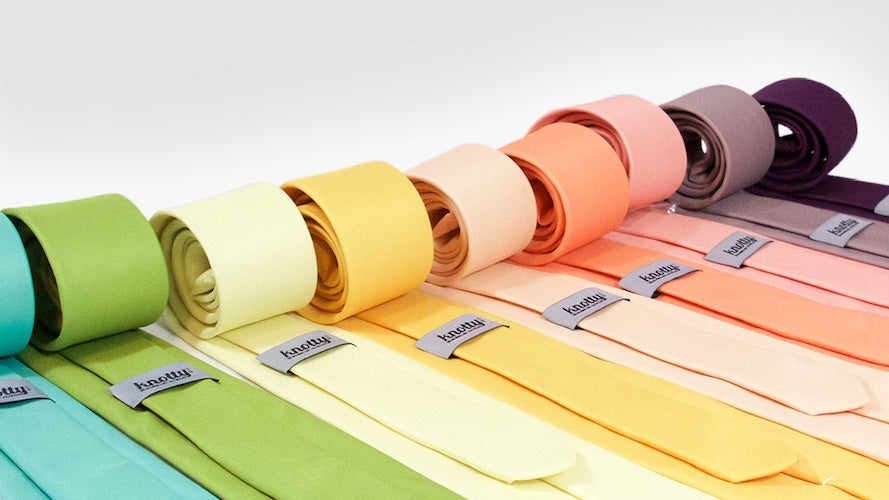 Solid colored neckties rolled and displayed on a table.