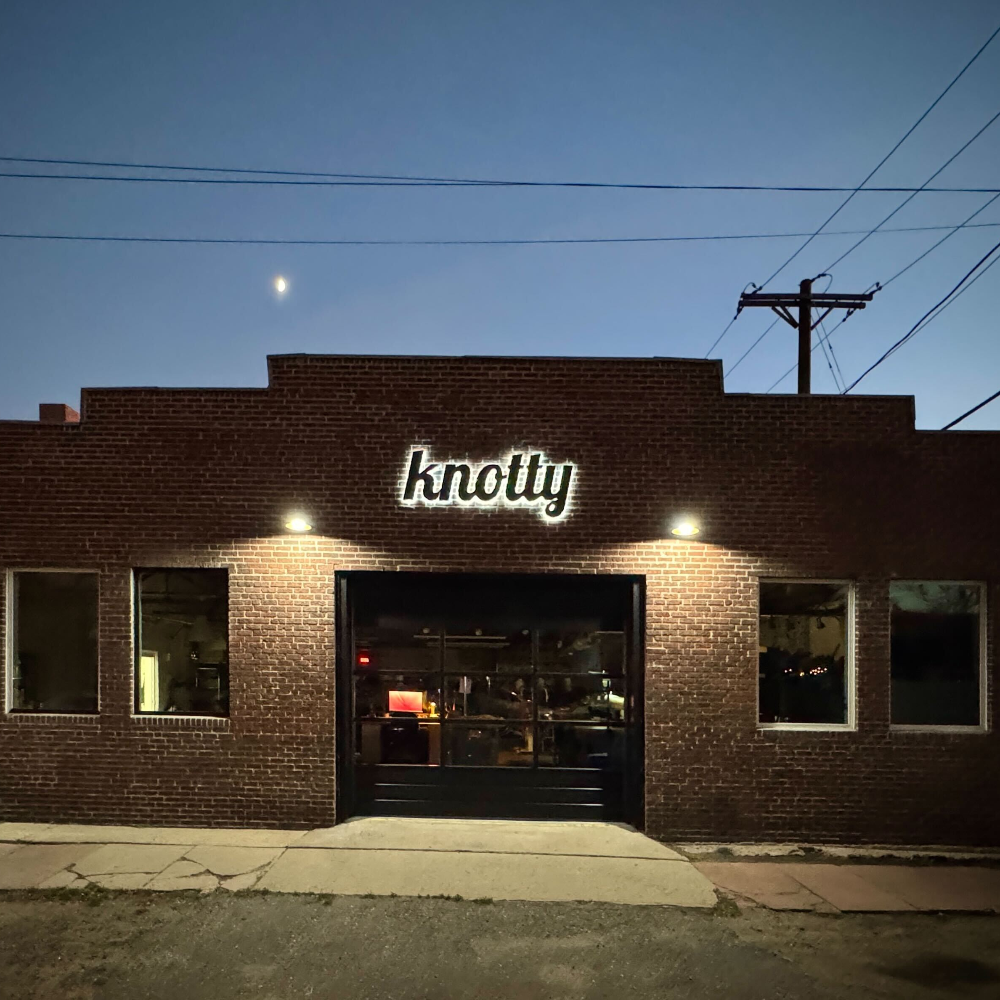 Brick building with 'knotty' sign at night