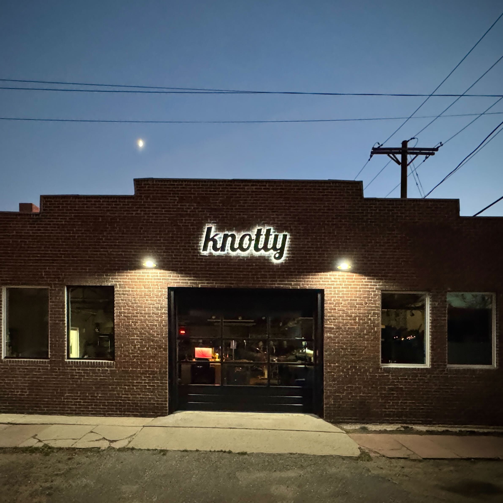 Brick building with 'knotty' sign at night