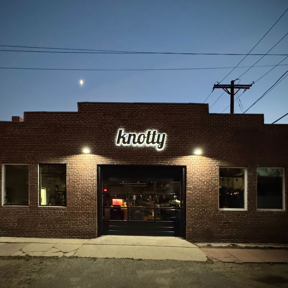 Brick building with 'knotty' sign at night