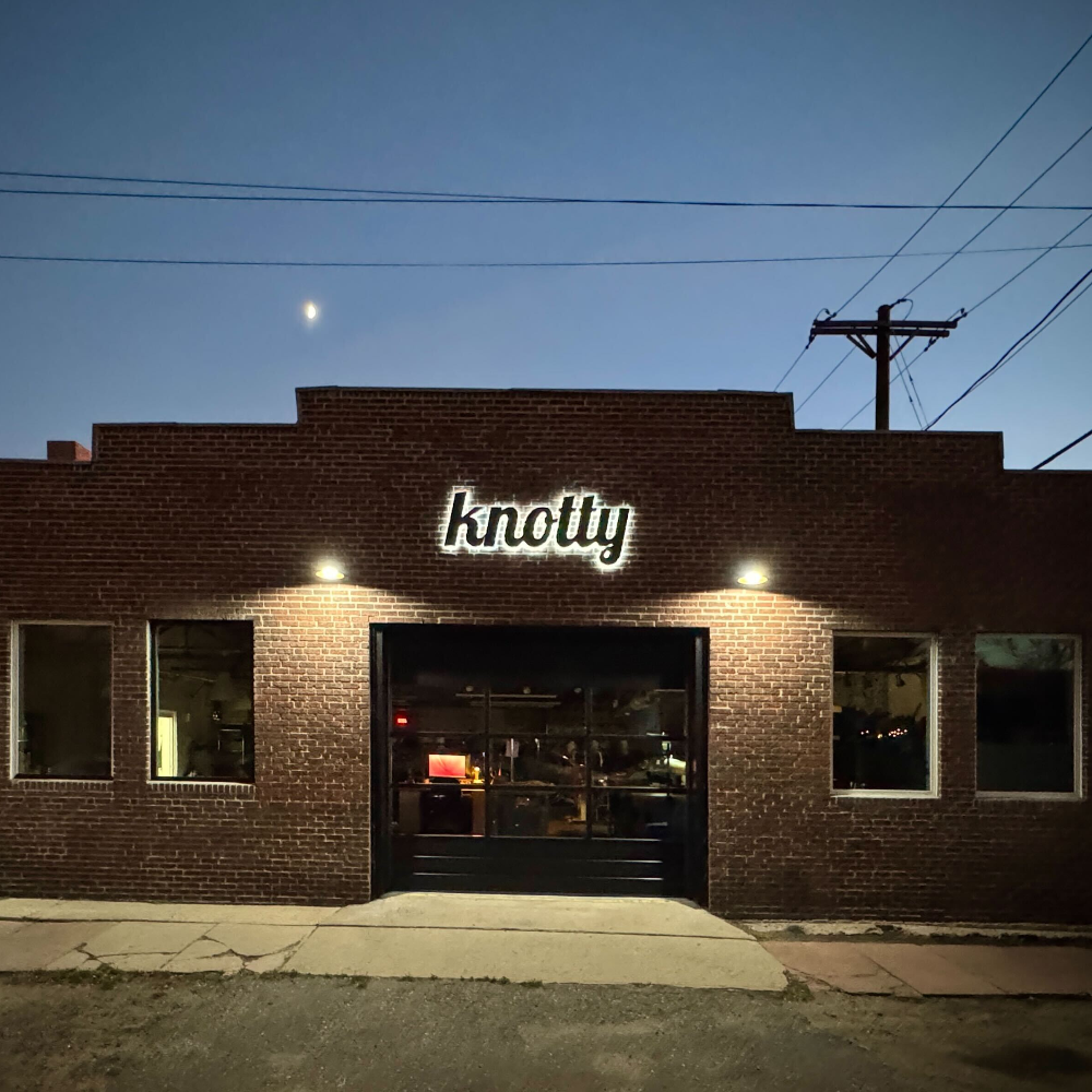 Brick building with 'knotty' sign at night