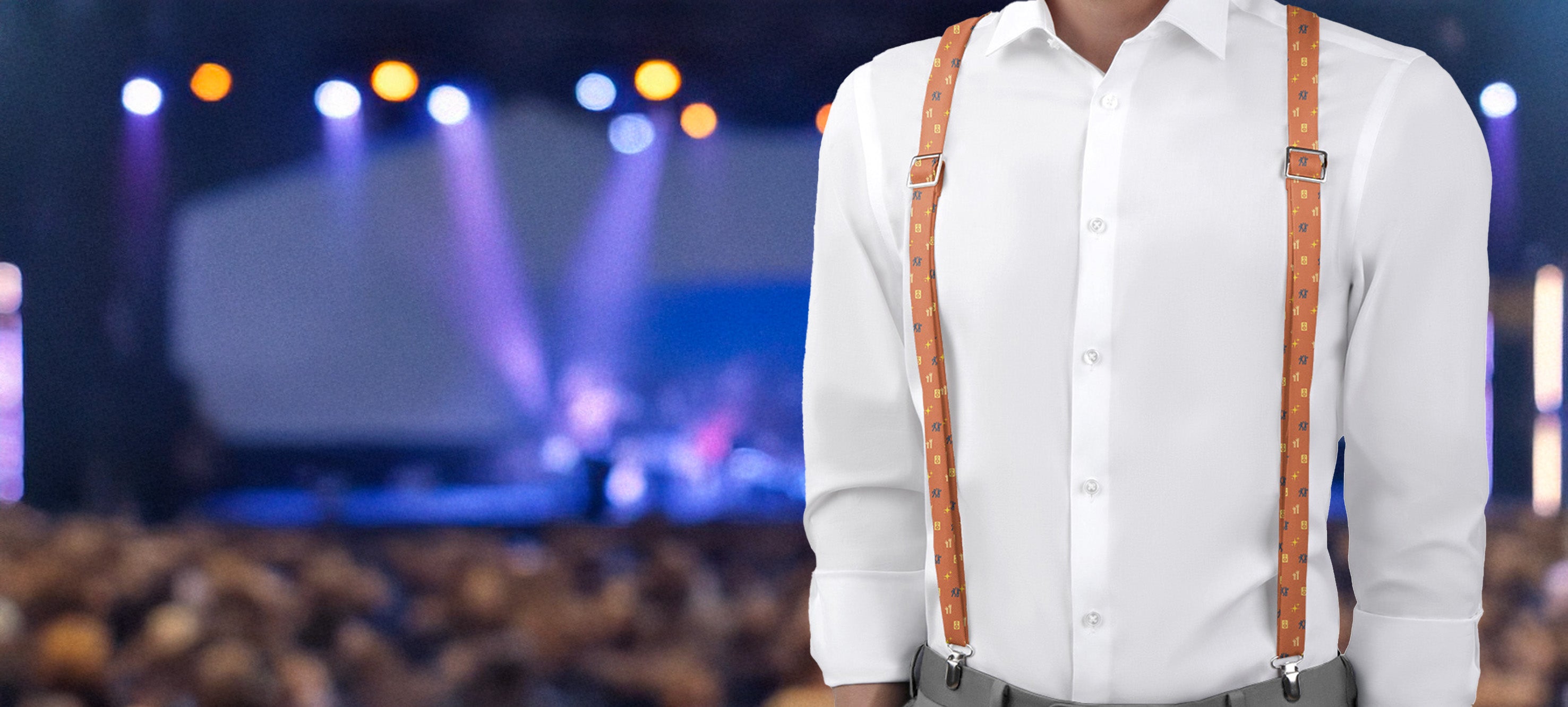 Person wearing a white shirt and brown friendship themed suspenders in front of a blurred audience and stage background